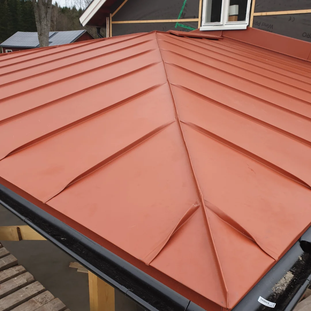 Valmat plåttak i tegelröd aluminium med svart takavvattning